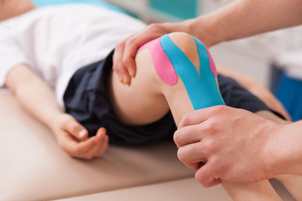 Physiotherapist doing with child exercise for knee
